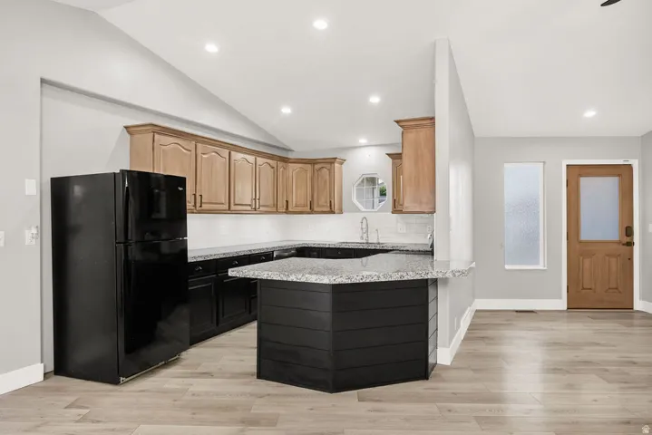 Kitchen featuring wood-finish cabinetry, black base cabinetry, and granite countertops