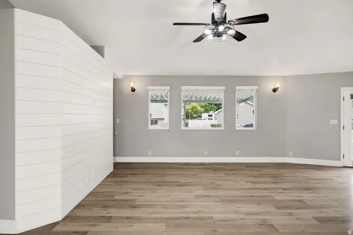 Spacious room featuring wood-finish flooring, a shiplap accent wall, and multiple windows