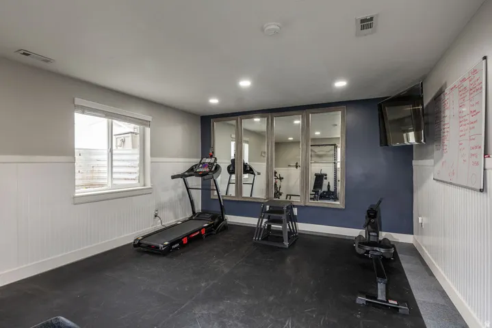 Dedicated exercise space featuring rubber flooring, recessed lighting, and a white beadboard wainscoting
