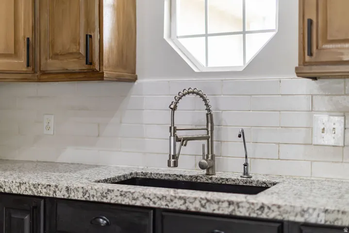Kitchen sink area featuring a stainless steel coiled faucet, under-mount sink, and granite countertops