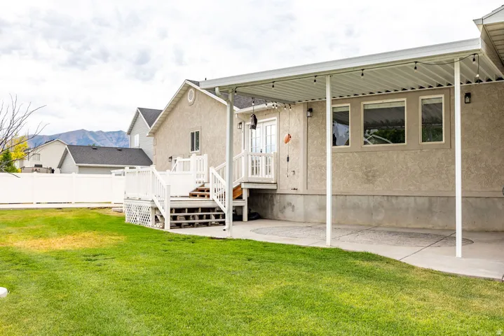 Expansive backyard featuring a lush lawn, white privacy fencing, and a multi-level  deck with baluster railing
