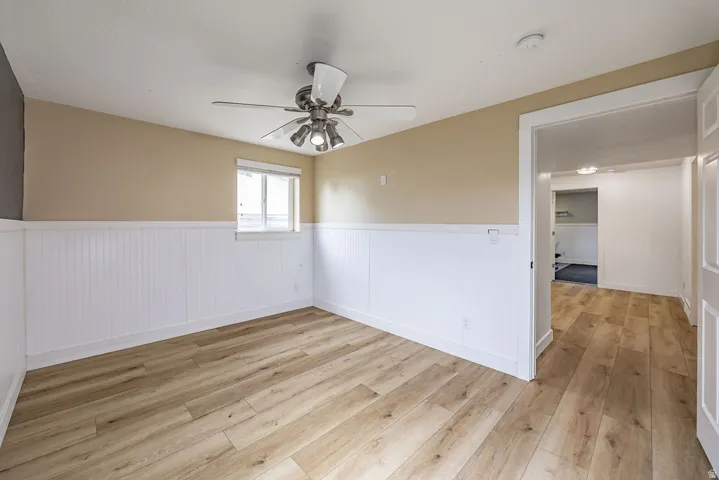 Room featuring wood-finish flooring, white beadboard wainscoting, and a large walk in closet