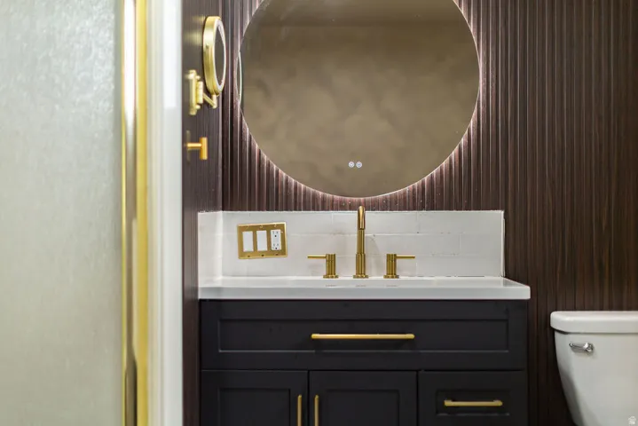 Master Bathroom vanity featuring a dark wood-finish cabinet with gold-tone hardware, a white countertop, and a white subway tile backsplash