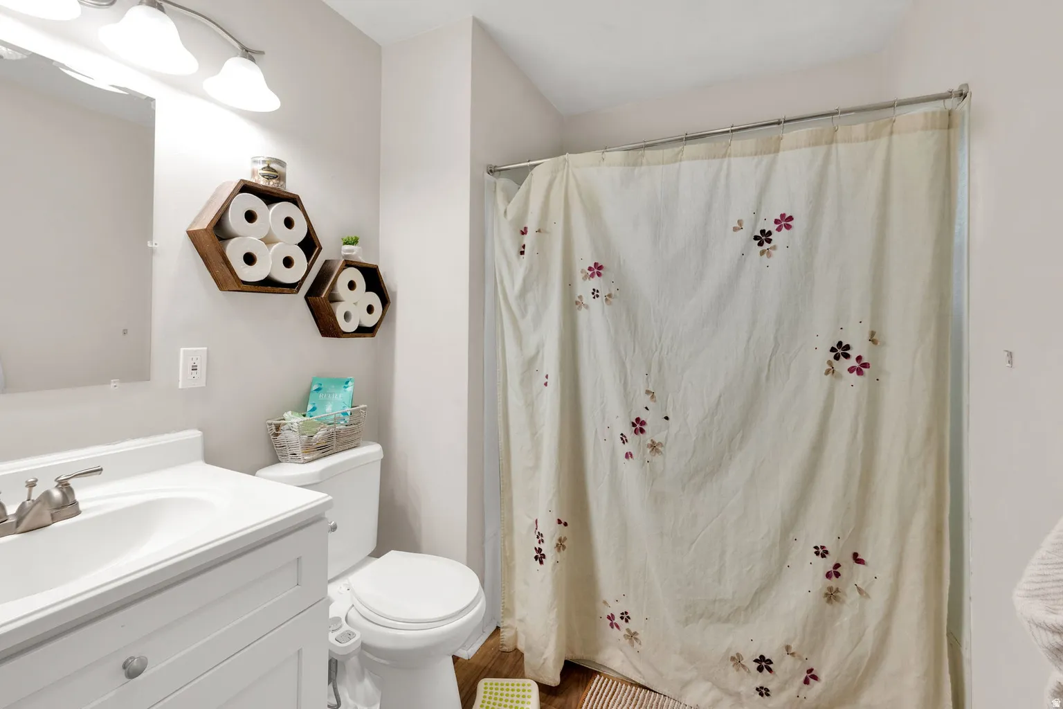 Bathroom featuring a single vanity with an integrated sink, brushed nickel faucet, and overhead sconce lighting