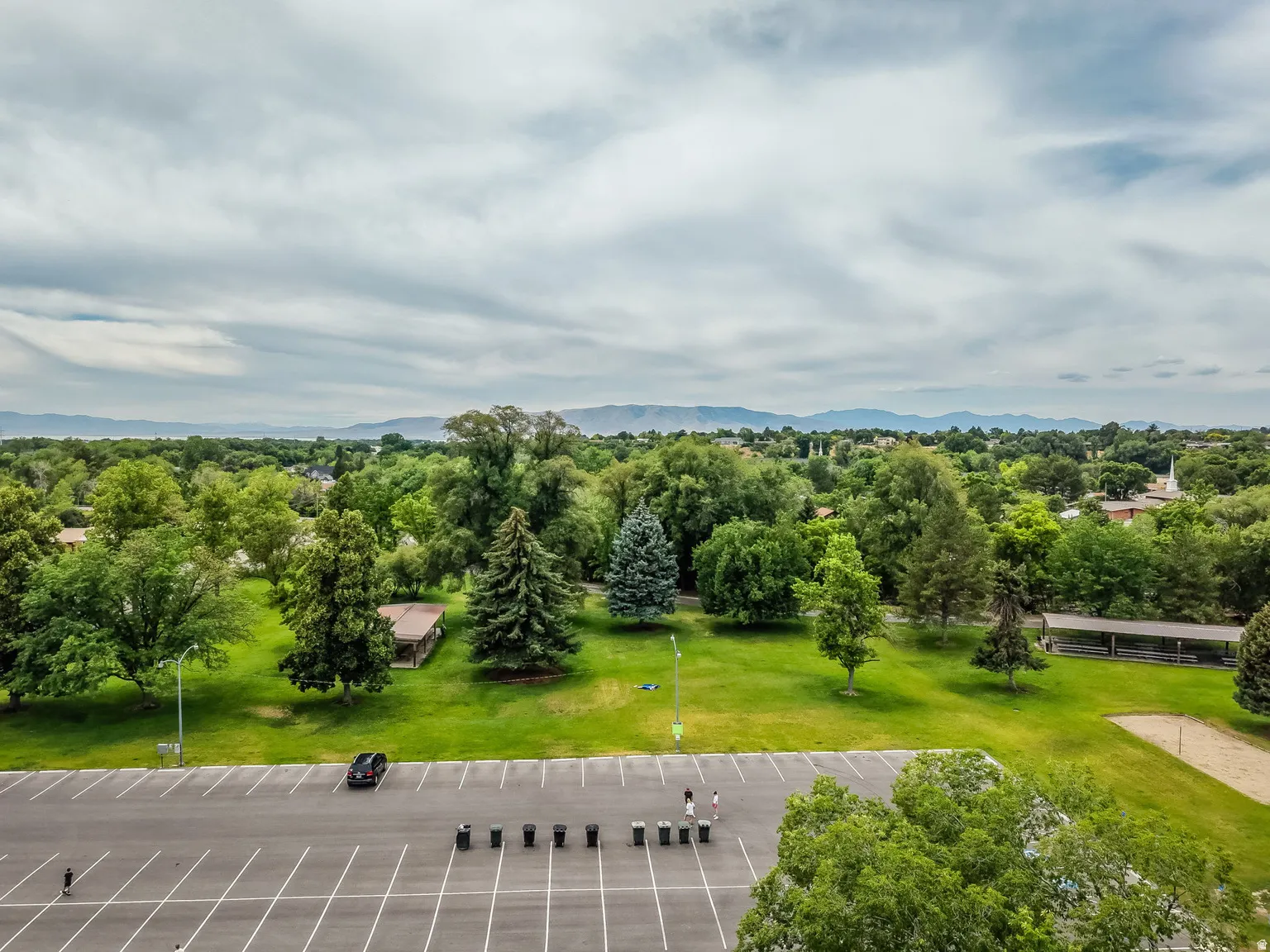 Expansive green space featuring mature trees and a paved parking area