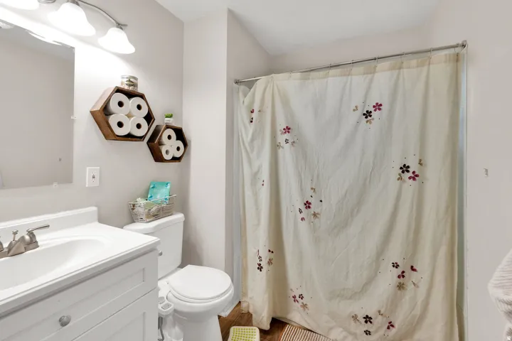 Bathroom featuring a single vanity with an integrated sink, brushed nickel faucet, and overhead sconce lighting