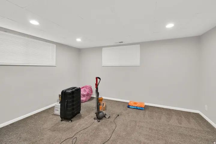 Finished room with neutral gray walls, recessed lighting, and two windows with blinds