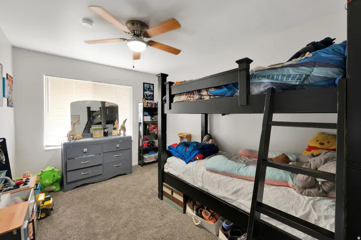 Carpeted room featuring a ceiling fan with light fixture, a window with blinds, and light-toned walls