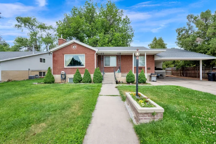 Brick exterior residence featuring a front lawn with a concrete pathway leading to the entry