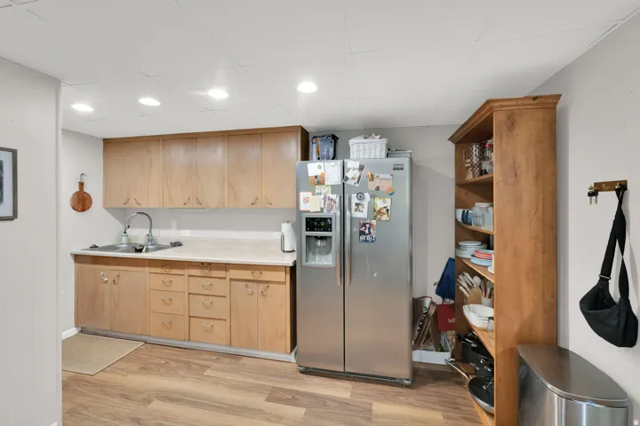 Kitchenette featuring wood-finish cabinetry, a stainless steel sink, and wood-finish flooring
