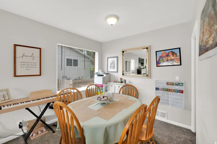 Dining space featuring light gray walls, a window with exterior views, and neutral-toned carpeting