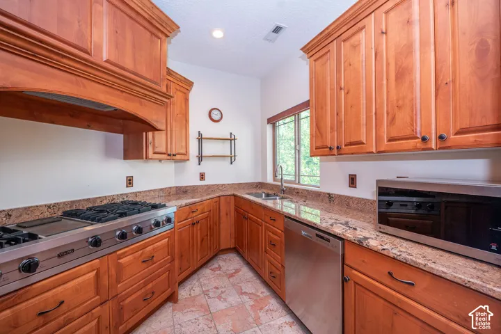 Second Level Kitchen featuring wood cabinetry, stainless steel appliances, granite countertops, and tile flooring