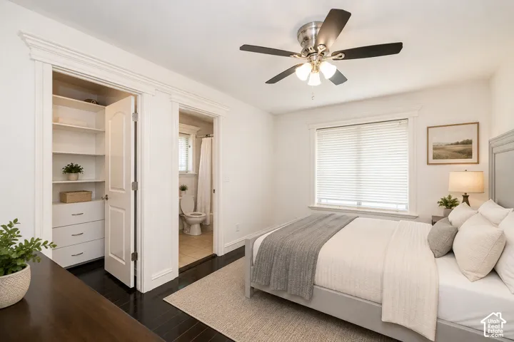Bedroom with dark wood-finish flooring, a ceiling fan with integrated lighting, and a window with blinds. Bedroom includes an ensuite.