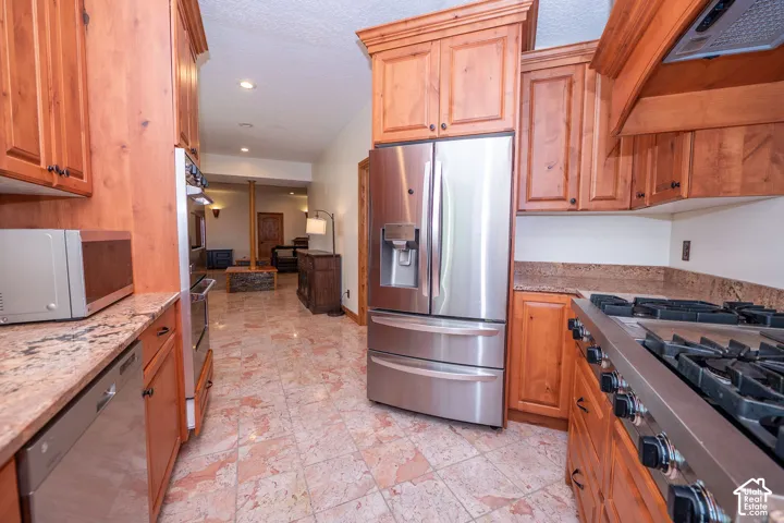 Second Level Kitchen featuring wood cabinetry, stainless steel appliances, granite countertops, and tiled flooring