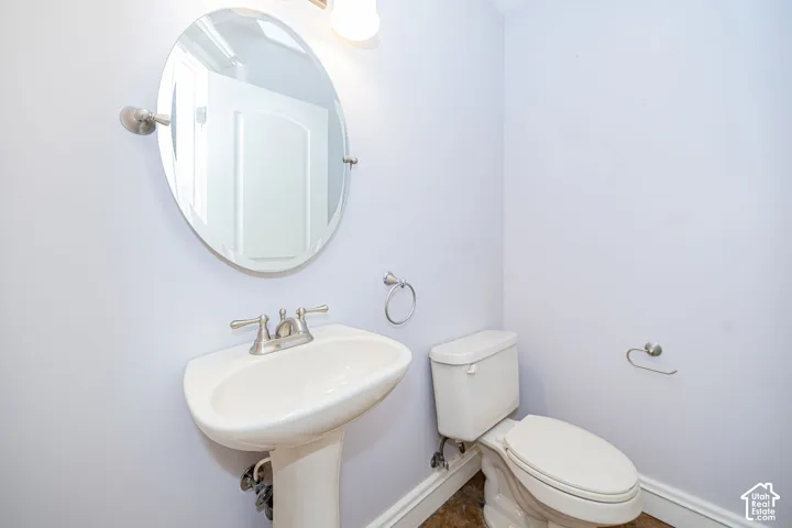 Compact half bathroom featuring a white porcelain pedestal sink, oval mirror, and brushed nickel fixtures