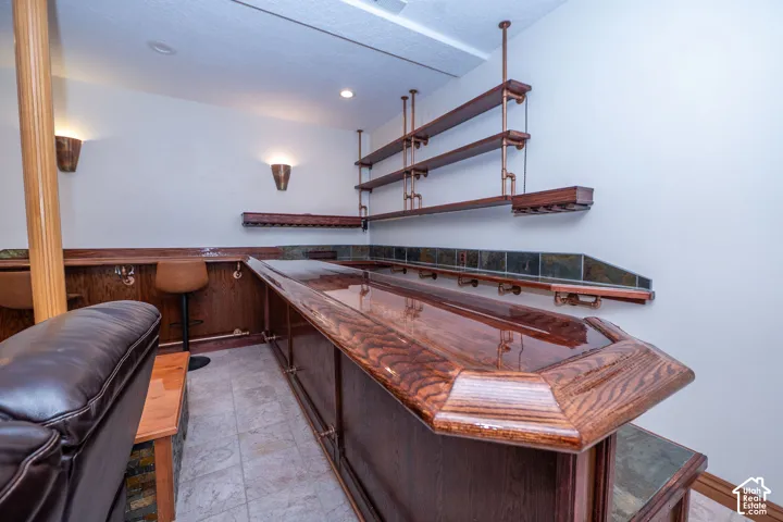 Custom-built bar featuring a high-gloss wood-finish countertop, coordinating wall-mounted shelving, and integrated lighting