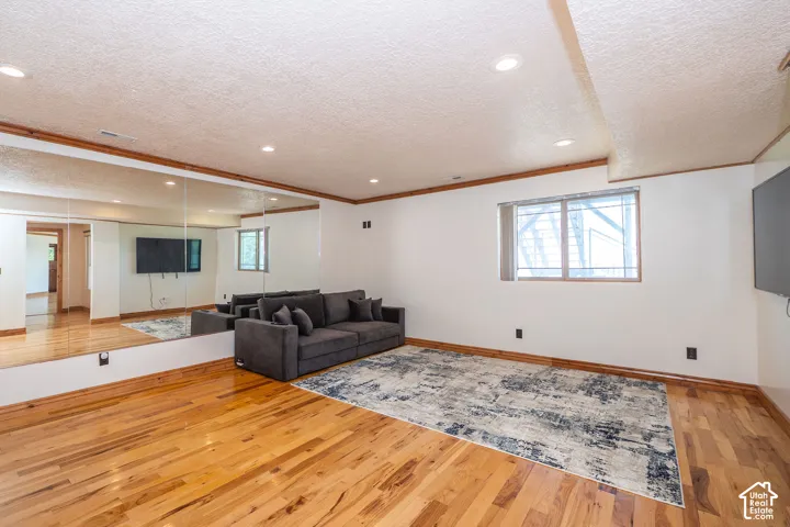 Spacious Fitness Room featuring wood-finish flooring and a full wall of mirrors, walk in sauna, walk in oversized shower and a bathroom.
