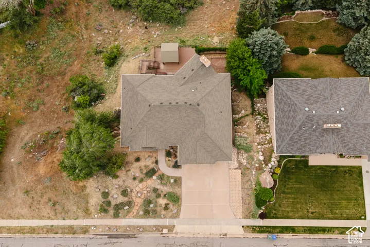 Residential property featuring an asphalt shingle roof, an attached garage, a concrete driveway, a wood deck, and a landscaped front yard with a stone path