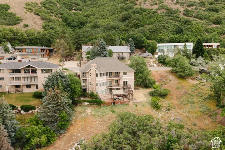 Exterior featuring a multi-level design with stone and stucco finishes, multiple balconies, a spacious wood-finish deck, and mature evergreen landscaping