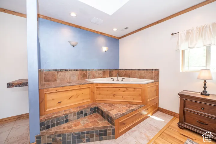 Built-in corner soaking tub with natural wood paneling and stone tile surround