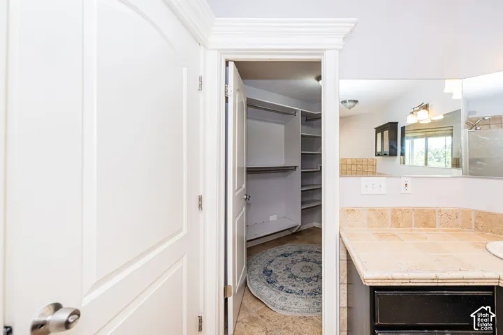 Walk-in closet with built-in shelving and tile flooring. Master bedroom closet.