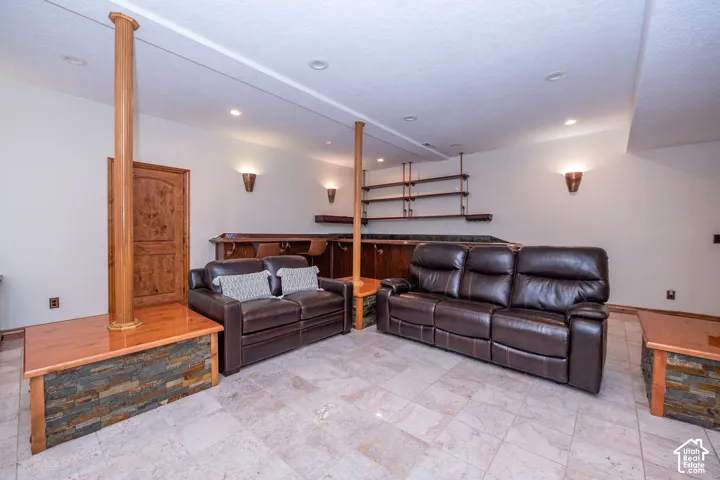 Spacious entertainment area featuring light-toned tile flooring and recessed lighting
