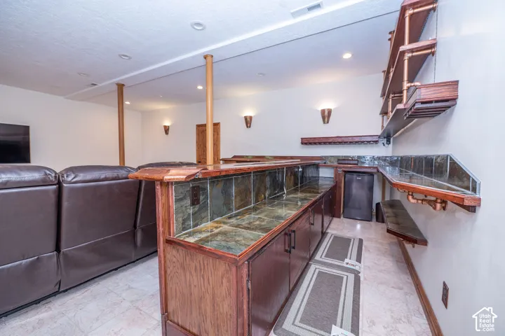Custom bar area featuring wood cabinetry and a tiled counter