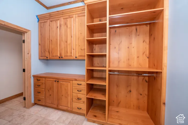 Custom wood-finish cabinetry and shelving with integrated hanging rods, complemented by a solid wood-finish countertop
