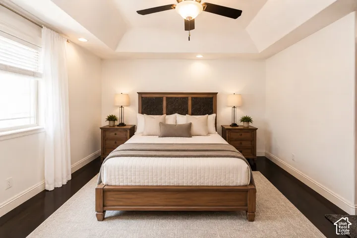 Spacious master bedroom featuring a tray ceiling with a ceiling fan and recessed lighting