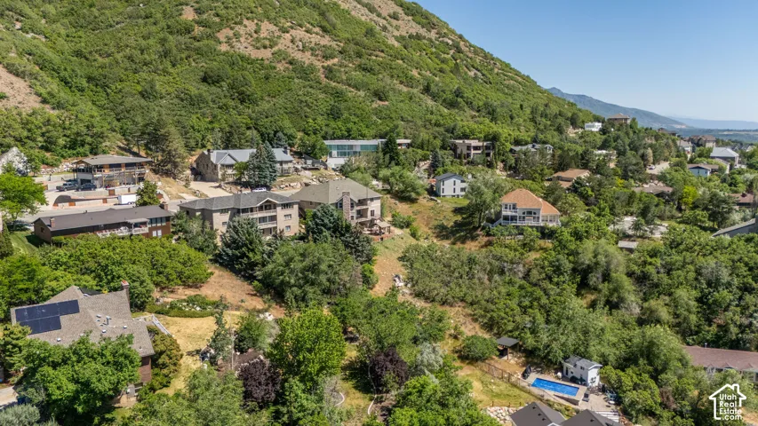 Hillside property surrounded by mature trees, featuring multiple levels and a sloped terrain