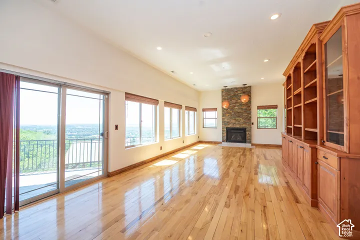 Level 2 Spacious living area featuring expansive wood-finish flooring, a built-in media center with shelving and glass-front cabinetry, and a fireplace with a stacked stone surround. 10 ft. ceilings.