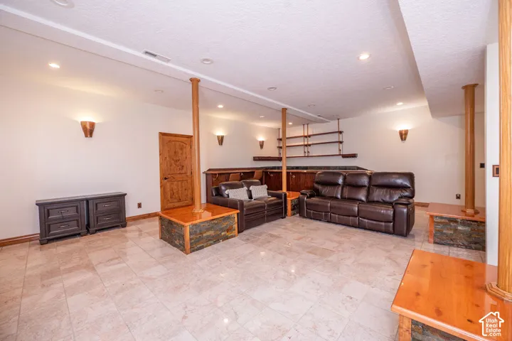 Spacious room featuring light-toned tile flooring, recessed ceiling lighting, and sconce wall lighting