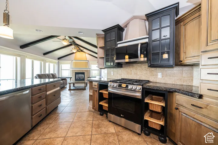 Open-concept kitchen featuring tile flooring, stainless steel range with overhead microwave, granite-finish countertops, and a tile backsplash
