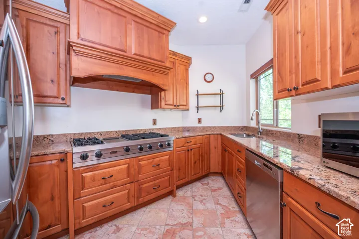 Second Level Spacious kitchen featuring warm wood cabinetry, granite countertops, stainless steel appliances, a six-burner gas range, and tile flooring
