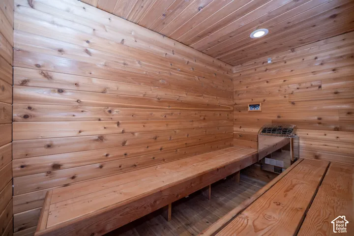 Oversized Interior sauna featuring natural wood paneling, built-in benches, recessed ceiling lighting, and a wall-mounted heater with controls