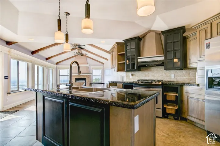 Gourmet kitchen featuring a large central island with an undermount sink, granite-finish countertops, stainless steel appliances, and a tiled backsplash