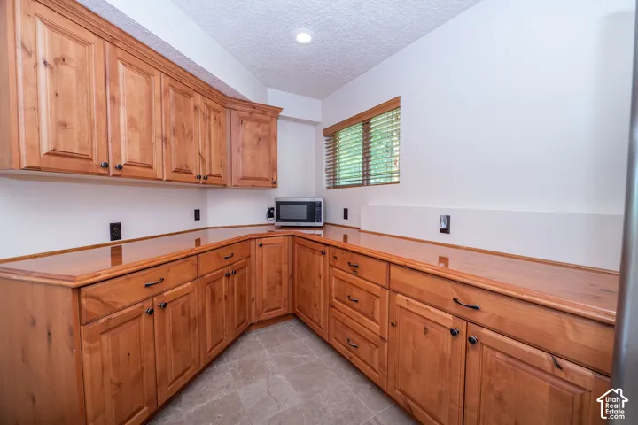Third level Kitchenette featuring extensive wood cabinetry, coordinating wood countertops, and grey tile flooring