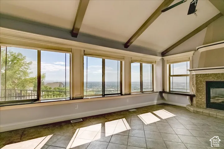 Expansive room featuring multiple windows, a high vaulted ceiling with exposed beams, and tile flooring