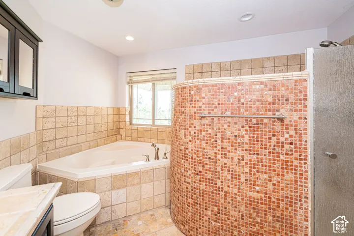 Master bathroom featuring a tiled corner soaking tub, a curved shower enclosure with mosaic tile, glass shower door, and a recessed ceiling light