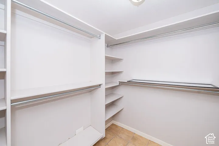 Walk-in master closet featuring built-in shelving, multiple hanging rods, and tile flooring