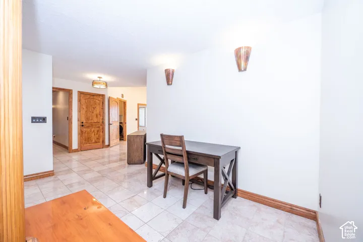 Hallway featuring light-toned tile flooring, wood-finish interior doors, and recessed lighting
