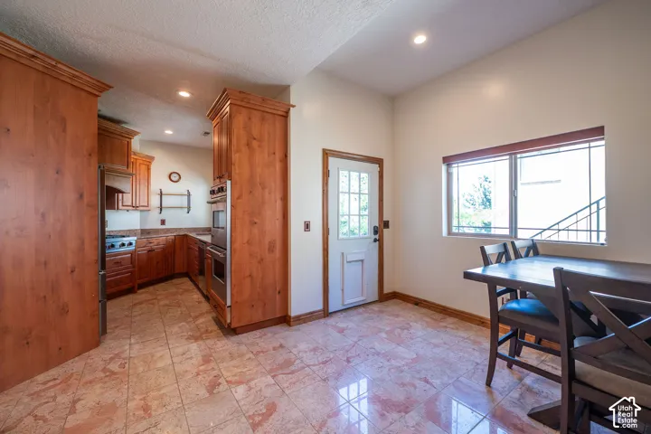 Second Level Kitchen and dining area featuring wood cabinetry, stainless steel appliances, granite countertops, and tile flooring