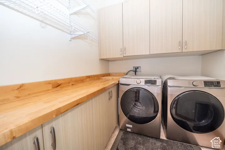 Laundry area featuring light wood-finish cabinetry, a natural wood countertop, and wire shelving