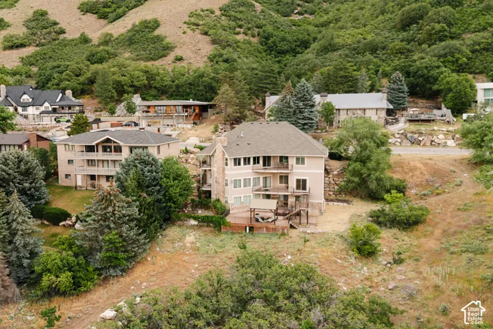 Multi-level residence featuring a light-colored stucco exterior with stone accents, multiple balconies, and a lower-level deck