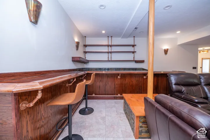 Built-in bar featuring wood paneling, a polished wood counter, and open shelving with metal accents