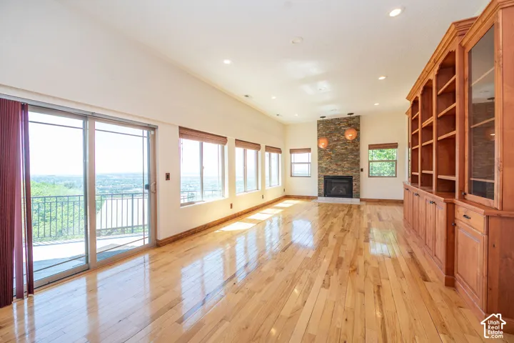Level 2 Spacious living area featuring expansive wood-finish flooring, a stone-clad fireplace with a hearth, and a built-in wood cabinetry unit. 10 ft. ceilings