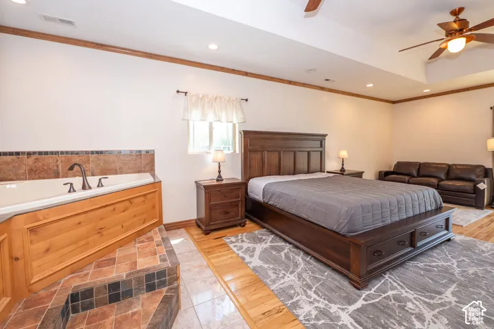 Recessed soaking tub with surrounding tilework, wood-finish paneling, and bronze-tone fixtures