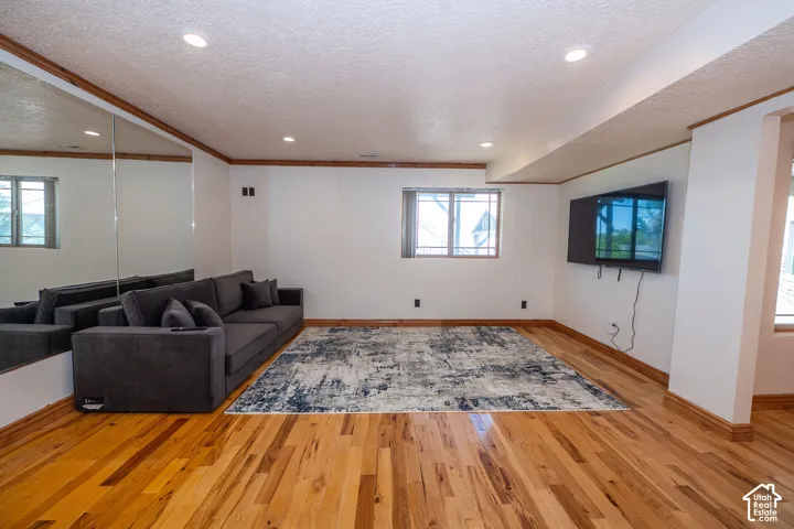 Fitness room interior with natural wood-finish flooring, recessed lighting, and a large mirrored wall feature