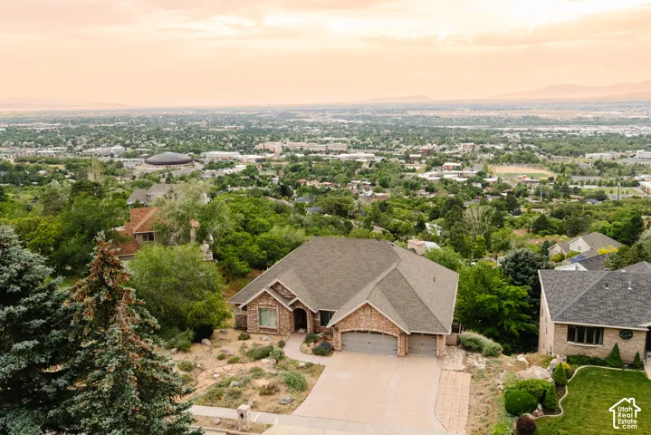 Stone-clad residence featuring a multi-car garage, pitched roofline, and an expansive paved driveway