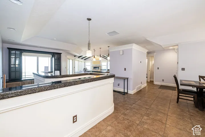 Open-concept living space with tiled flooring and a built-in wet bar featuring dark cabinetry and a granite-style countertop
